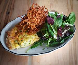 A quiche special with crispy shoestring potatoes and dressed greens