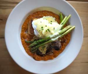 Grilled steak tips on toasted brioche in a bowl of lobster bisque and topped with asparagus, two poached eggs, and bearnaise