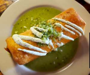 The chimi-chomelet special: an omelet wrapped in a tortilla and fried until crispy, topped with salsa verde and sour cream